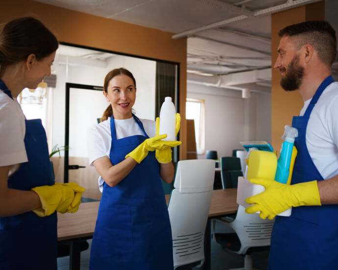 Profissionais de limpeza sorrindo e segurando produtos de limpeza